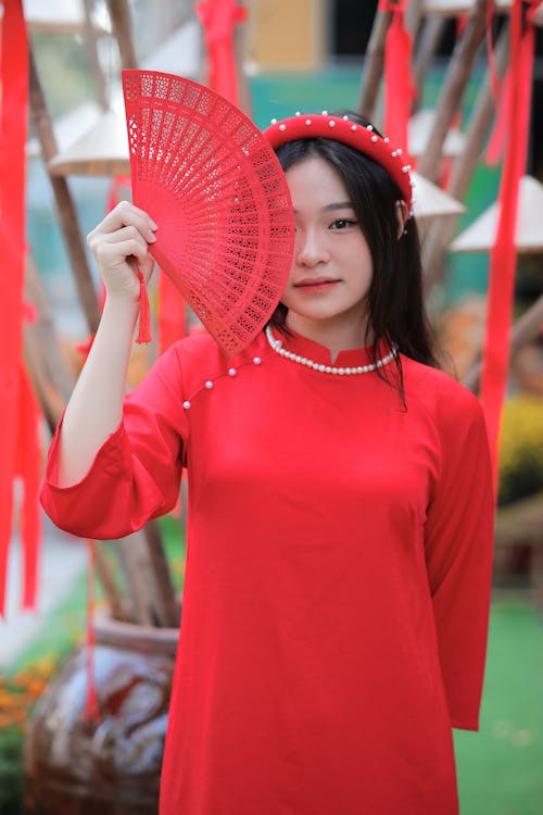 A woman in red holding a fan