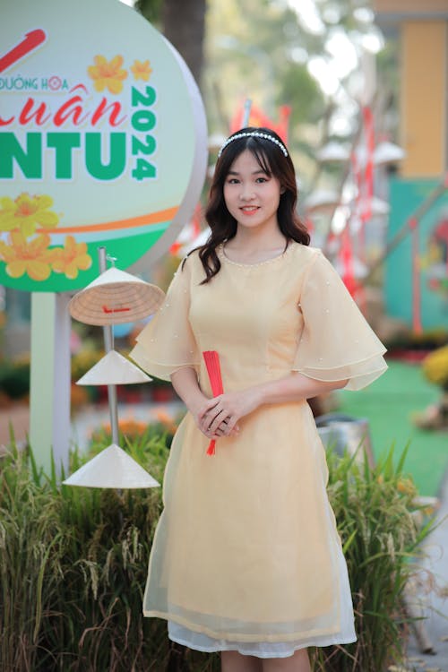 A woman in yellow dress standing next to a sign
