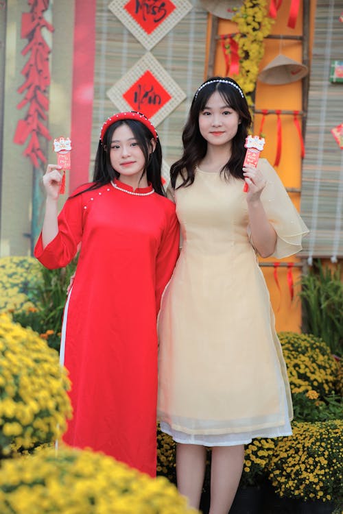 Two asian women in traditional dress holding up a box of chinese food
