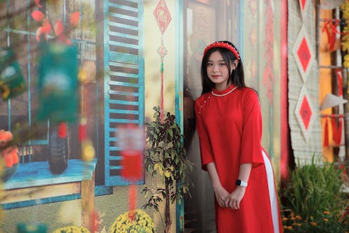 A woman in a red dress stands in front of a wall with colorful designs
