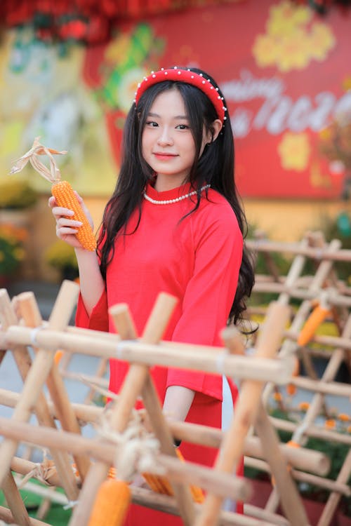 A girl in a red dress holding a carrot