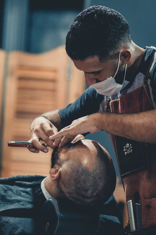 Free A skilled barber precisely shaving a client's head in a modern barbershop. Stock Photo