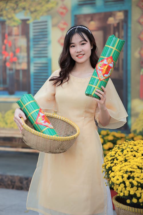 A woman holding a basket of flowers and a basket of rice