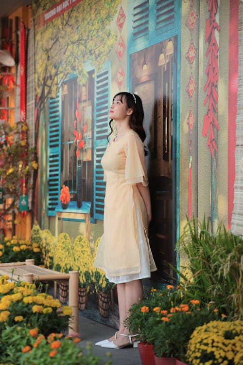 A woman in yellow dress standing in front of a wall