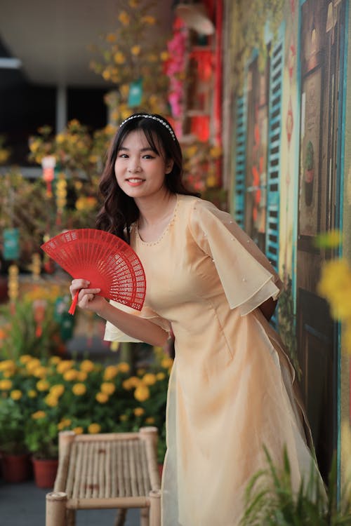 A woman in yellow dress holding a fan