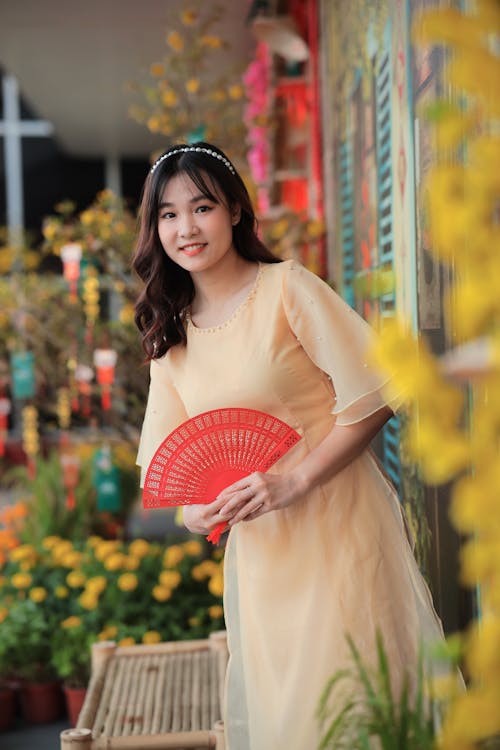 A woman in a yellow dress holding a red fan