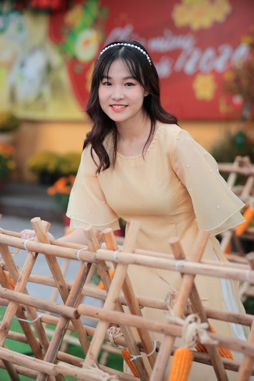 A woman in a yellow dress standing next to bamboo