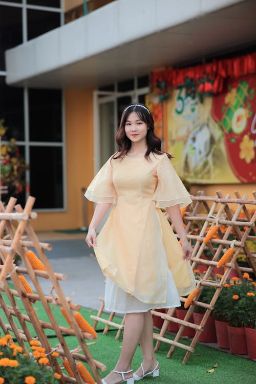 A woman in a yellow dress standing outside
