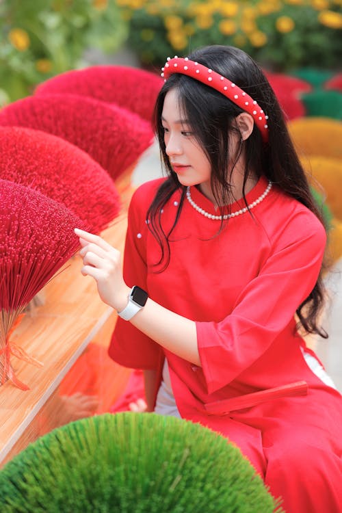 A woman in red is looking at some colorful flowers