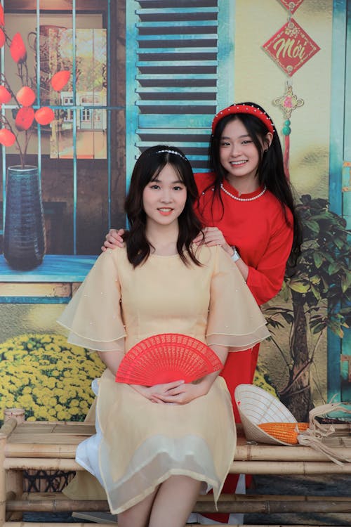 Two asian women pose for a photo in front of a wall