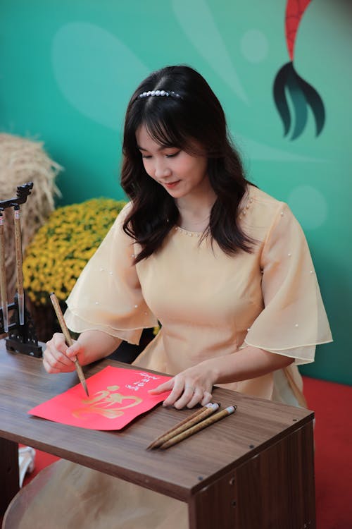 A woman is writing on a piece of paper with a red pen