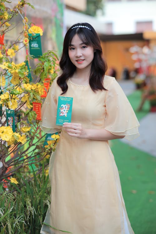 A woman in a yellow dress holding a book