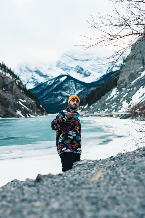 Man Posing in front of a Frozen Lake and Mountains in Winter 