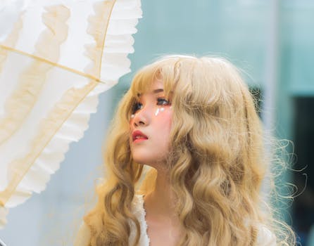 A close-up portrait of a woman in cosplay with elegant makeup, holding an umbrella.