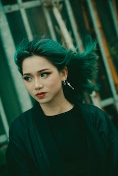 一位留着充满活力绿头发的年轻女子在城市环境中户外摆姿势