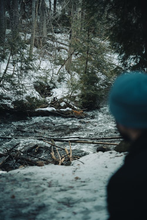 A man in a blue beanie looking at a river