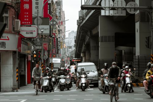Free A bustling city street filled with motor scooters, bicycles, and traffic. Stock Photo