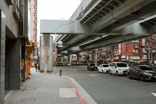 City street under viaduct in Taipei, Taiwan featuring cars and urban architecture.