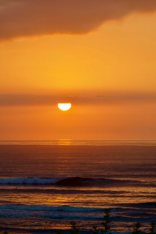 Free Beautiful golden sunset over the ocean in Cape Town. Perfect reflection on the water with scenic waves adding to the serene atmosphere. Stock Photo