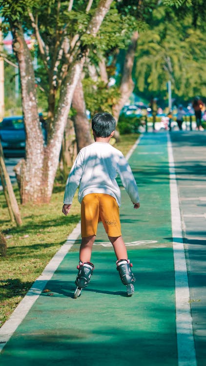 Back View of a Little Boy Roller Skating in a Park 