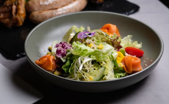 A vibrant and fresh salad featuring smoked salmon, lettuce, and edible flowers.