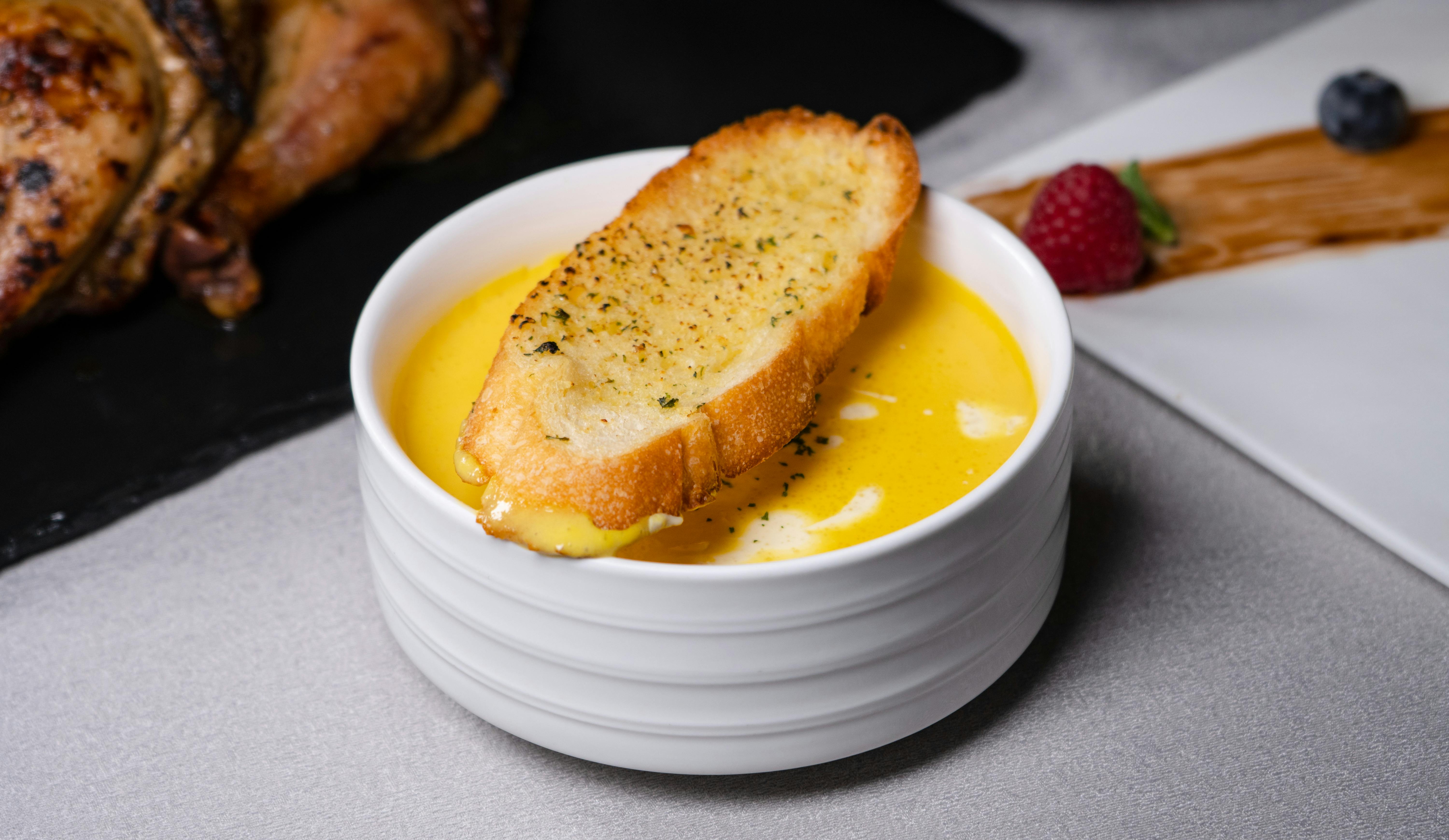 Close-up of a creamy soup served with garlic toasted bread in a modern setting.