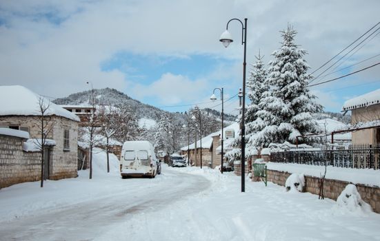 A tranquil snow-covered street in Voskopojë, Albania, showcasing winter scenery and architecture.