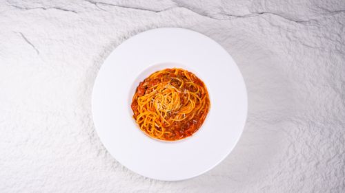 Free Top view of spaghetti pasta in a flavorful tomato sauce on a white plate, perfect for Italian cuisine concepts. Stock Photo