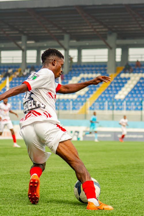 A soccer player in white and red is kicking the ball