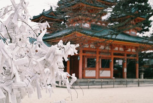 Omikuji fortune papers tied to tree branches near a traditional temple in Kyoto, Japan.