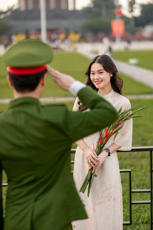 Soldier Saluting a Pretty Brunette Holding a Bunch of Flowers