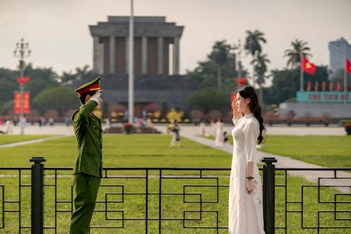 Soldier and a Young Brunette Wearing a White Dress Saluting in Front of the Ho Chi Minhs Mausoleum