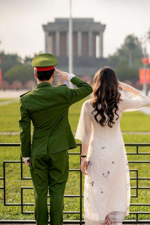 Soldier and a Young Woman Saluting Side by Side in Front of the Ho Chi Minh's Mausoleum