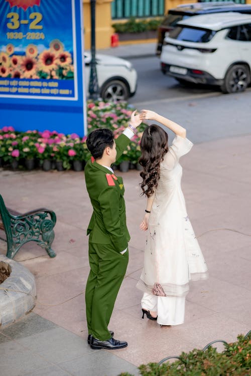 Man Wearing a Military Uniform Holding Hands with a Young Woman Wearing a White Dress