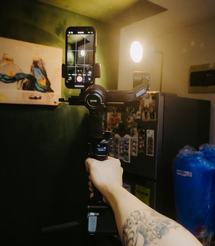 Braço segurando smartphone em gimbal, bastidor de filmagem