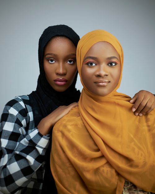 Free Sophisticated studio portrait of two young women in stylish, colorful hijabs, exuding elegance and confidence. Stock Photo