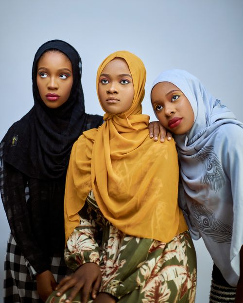 Free Three young women wearing brightly colored hijabs posing together on a white backdrop. Stock Photo