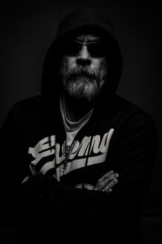 一幅戏剧性的黑白肖像画中，一位戴着太阳镜、留着胡须的男人散发着神秘感