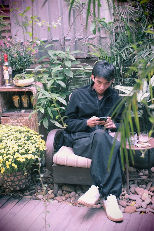 A woman sitting on a chair in a garden using a cell phone