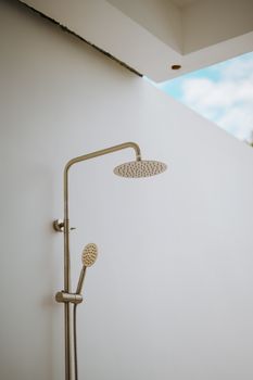 An outdoor shower against a white wall, perfect for summer retreats.