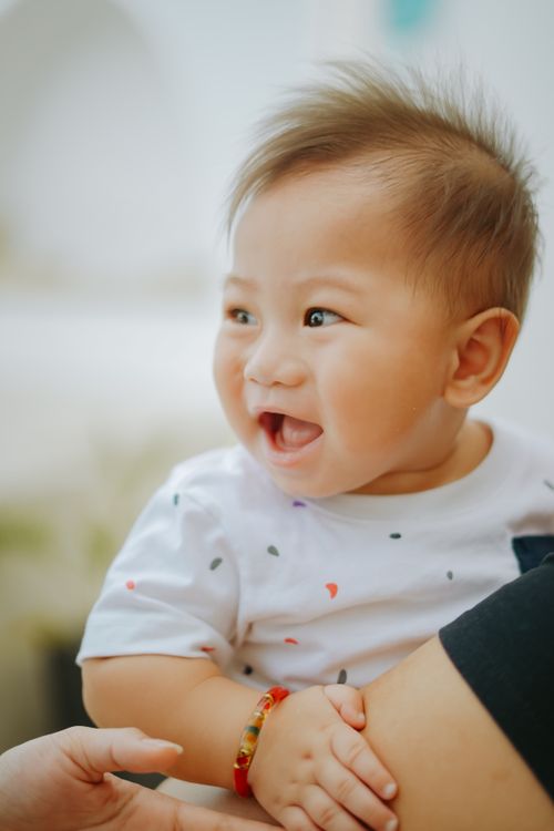 Free Adorable Asian baby with brown hair smiling in a close-up portrait. Stock Photo