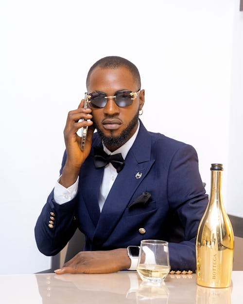 A man in a suit and sunglasses talking on the phone