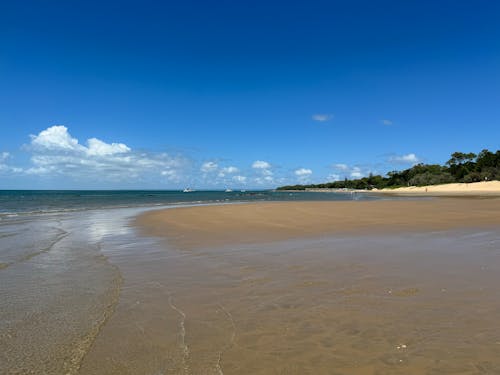 A sandy beach with blue sky and water