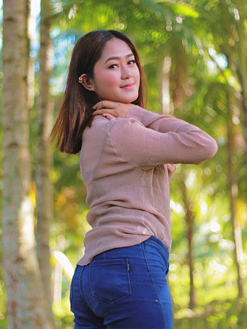 A young woman posing in the woods wearing jeans