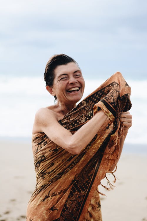 Photo of a Woman with Short Hair Standing on a Beach and Smiling