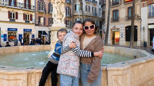 Close up of pre-teen friends in a square at fountain hugs and smiling to camera