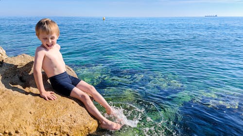 Happy kid at the sea having fun and splashing water in summer