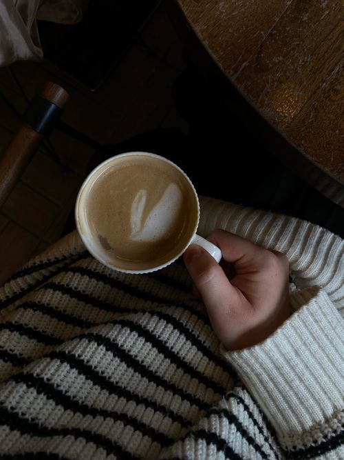Free Close-up of a latte art coffee held by a person in a cozy sweater in an İstanbul café. Stock Photo