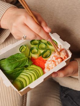 Close-up of a fresh takeout meal with avocado, cucumber, and crab, perfect for a healthy lunch.