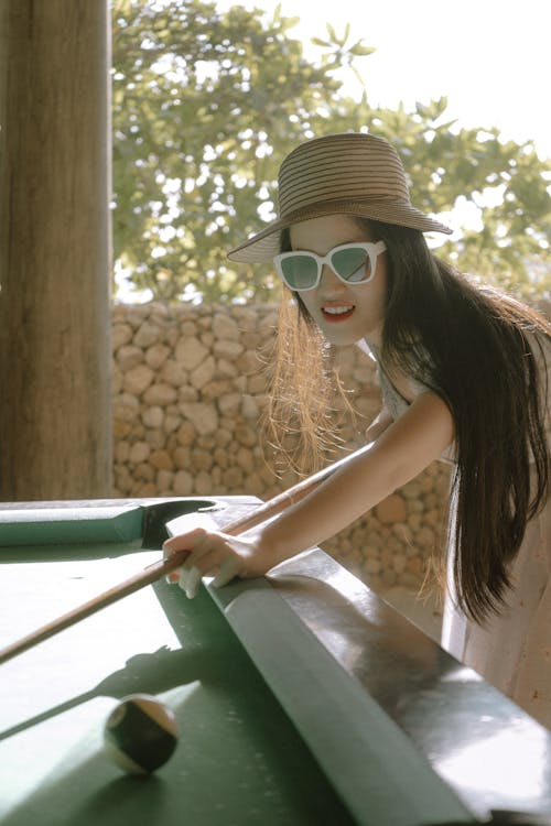 Young Woman in a Sunhat and Sunglasses Playing Billiard 